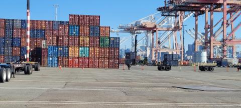 A port harbor with a tall stack of shipping containers and cranes.