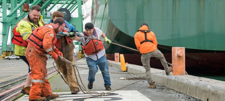 Longshore workers pulling line of a ship